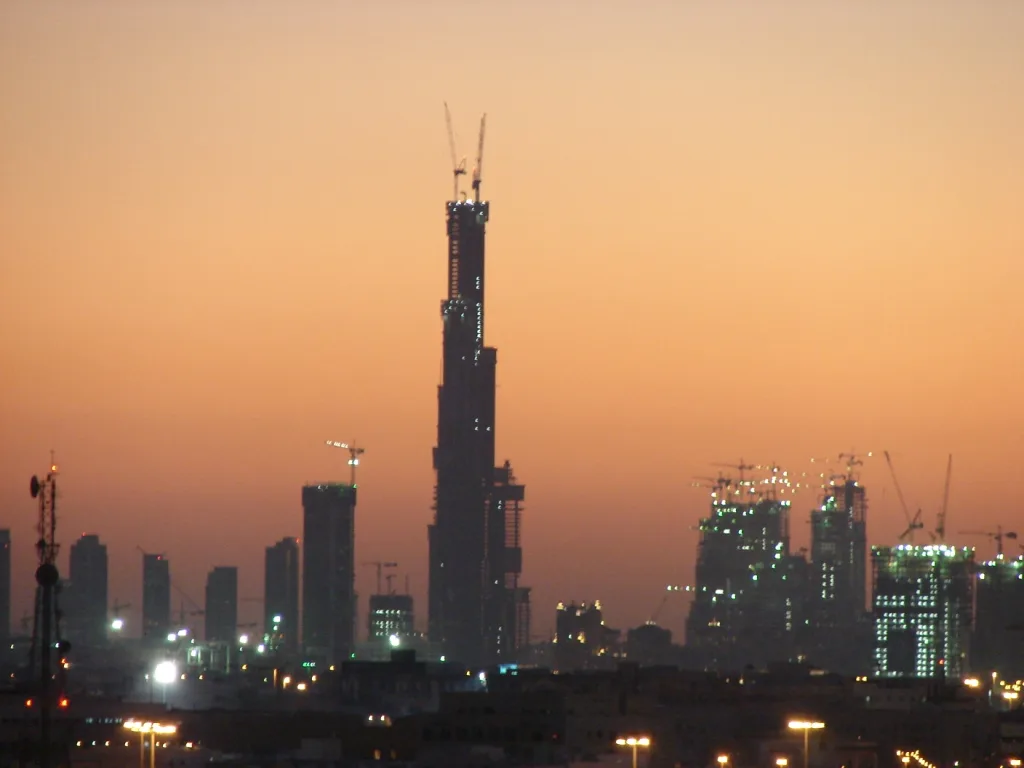 A supertall skyscraper under construction against a dusk sky